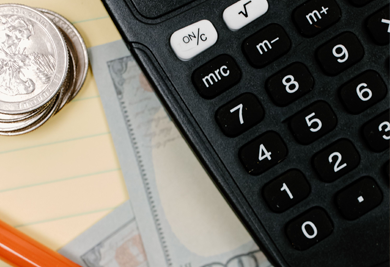 doing finances at a table with cash, a pencil and a calculator