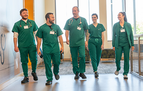 five nursing students walk along the TRC allied health building hallways in green scrubs