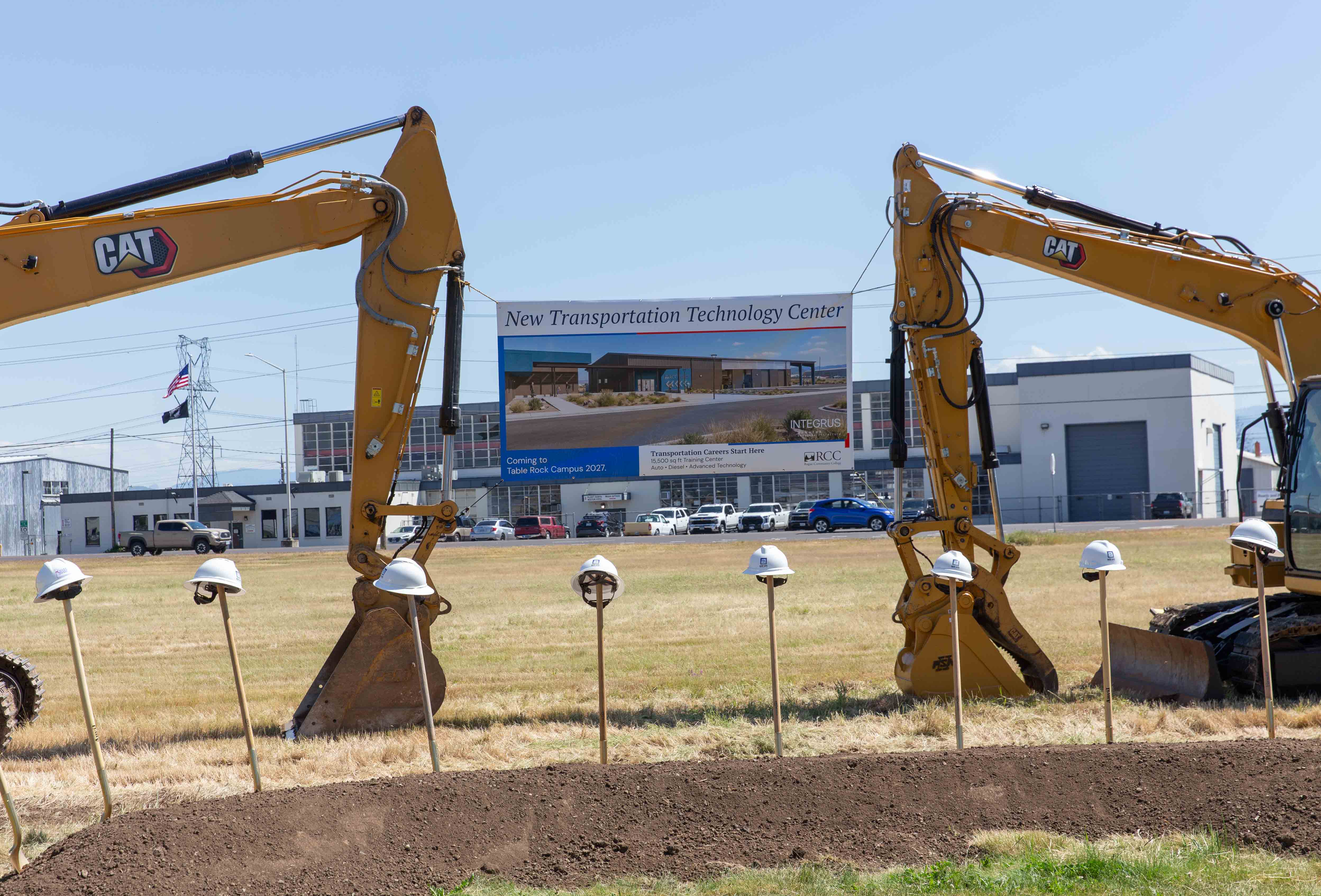a new sign sits at the site of the future transportation technology center, held tight by two large digger tractors